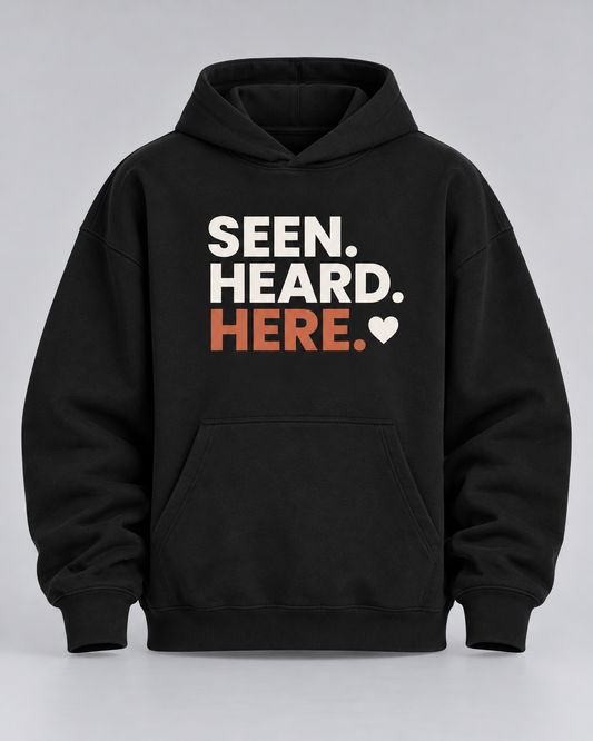 Hoodie „Seen. Heard. Here.“ schwarz – Produktfoto (KI-generiert, Druck entspricht dem Original)